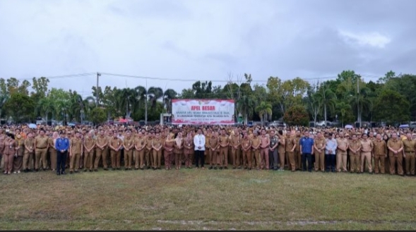 Ratusan ASN berkumpul mengikuti Apel Besar di Palangka Raya, dipimpin Wali Kota Fairid Naparin, dengan kerumunan besar yang menjadi latar belakang barisan rompi cokelat dan lanskap ladang hijau.