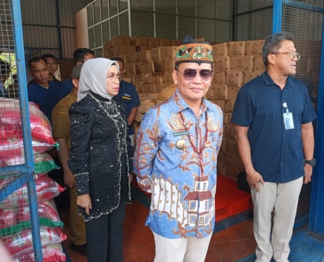 Dalam sidak Gudang Bulog di Palangka Raya, Agustiar Sabran mengecek stok beras dengan batik biru dan kacamata hitam.