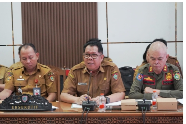 Darliansjah menghadiri rapat Pansus DPRD Provinsi Kalimantan Tengah membahas Raperda Penanaman Modal dan PTSP, berseragam cokelat dan berkacamata.