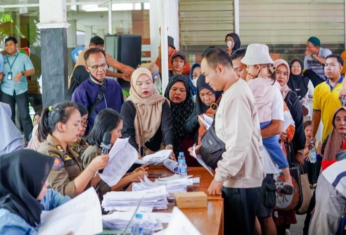 Suasana penyaluran Kartu Huma Betang Sejahtera (KHBS) tahap II di Palangka Raya dengan antrean penerima dan verifikasi dokumen, memakai masker.