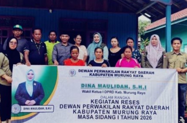 Sekelompok warga Desa Dirung Bakung bersama Wakil Ketua I DPRD Kabupaten Murung Raya Dina Maulidah berpose di balai desa dengan spanduk biru kegiatan reses.